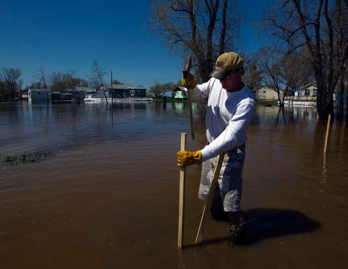 Bill Langdon marks out his driveway in the floodwaters in front of his home in Twin Beach in May 2011. THE CANADIAN PRESS/Ryan Remiorz