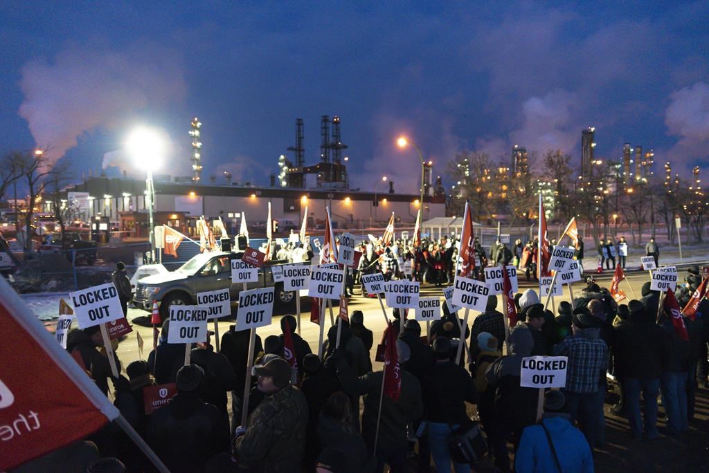 Regina police have charged four men in relation to a "confrontation" near the Co-op refinery Thursday. Pictured are members of Unifor Local 594 holding signs during a rally outside the Co-op Refinery on Dec. 5, 2019. 