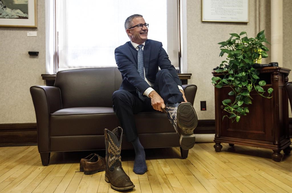 Alberta Finance Minister Travis Toews puts on a pair of cowboy boots during a pre-budget photo op in Edmonton on Wednesday, Oct. 23, 2019. Toews come on down, you've been voted Alberta's legislature member of the year. THE CANADIAN PRESS/Jason Franson.