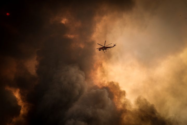 Helicopters dump water on bushfires as they approach homes located on the outskirts of the town of Bargo on Dec. 21, 2019 in Sydney, Australia.