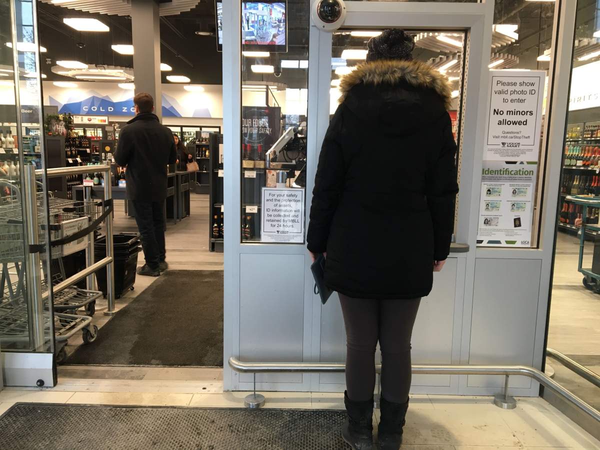 A customer waits at a new secure entrance installed at the Liquor Mart at Burnell Street and Portage Avenue.