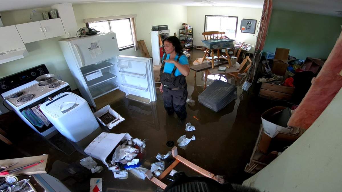 Jennifer Houghton shows the high water mark with her hand during the May 2018 floods.