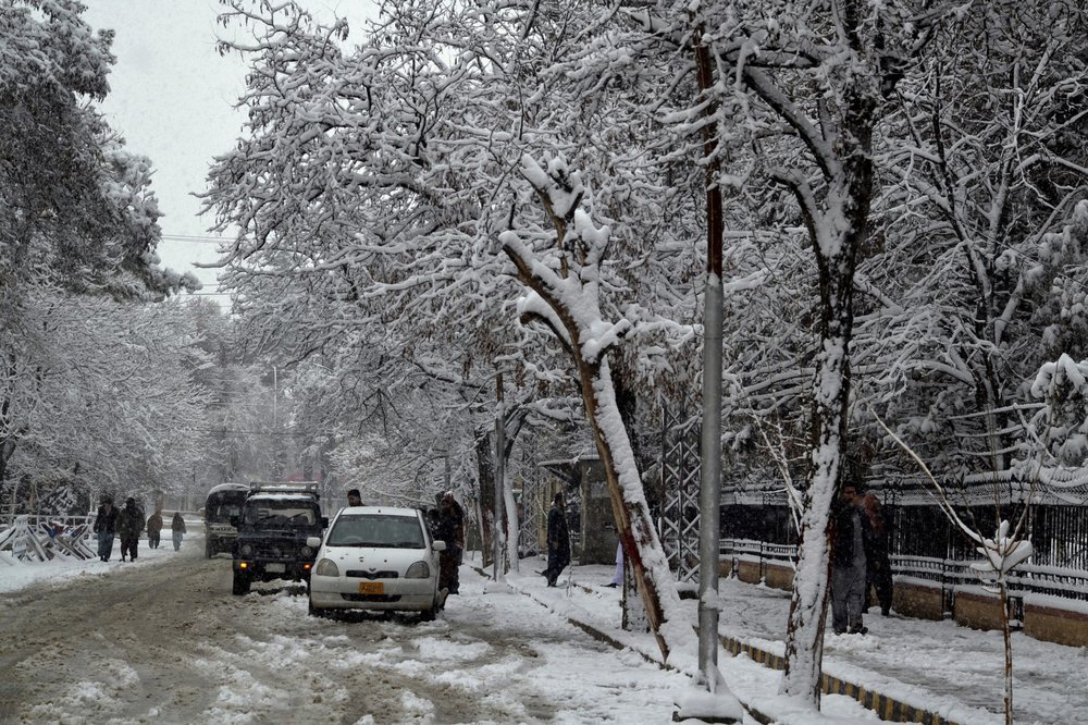 In this Sunday, Jan. 12, 2020, photo, people walk on a road during heavy snow fall in Quetta, capital of Pakistan's southwestern Baluchistan province. Much of the damage was caused in Pakistan's southwestern Baluchistan province where Imran Zarkon, the head of provincial disaster management authority said 14 people were killed in the past 24 hours because of roofs amid winter's unusual snowfall, which also blocked highways and disrupted normal life.