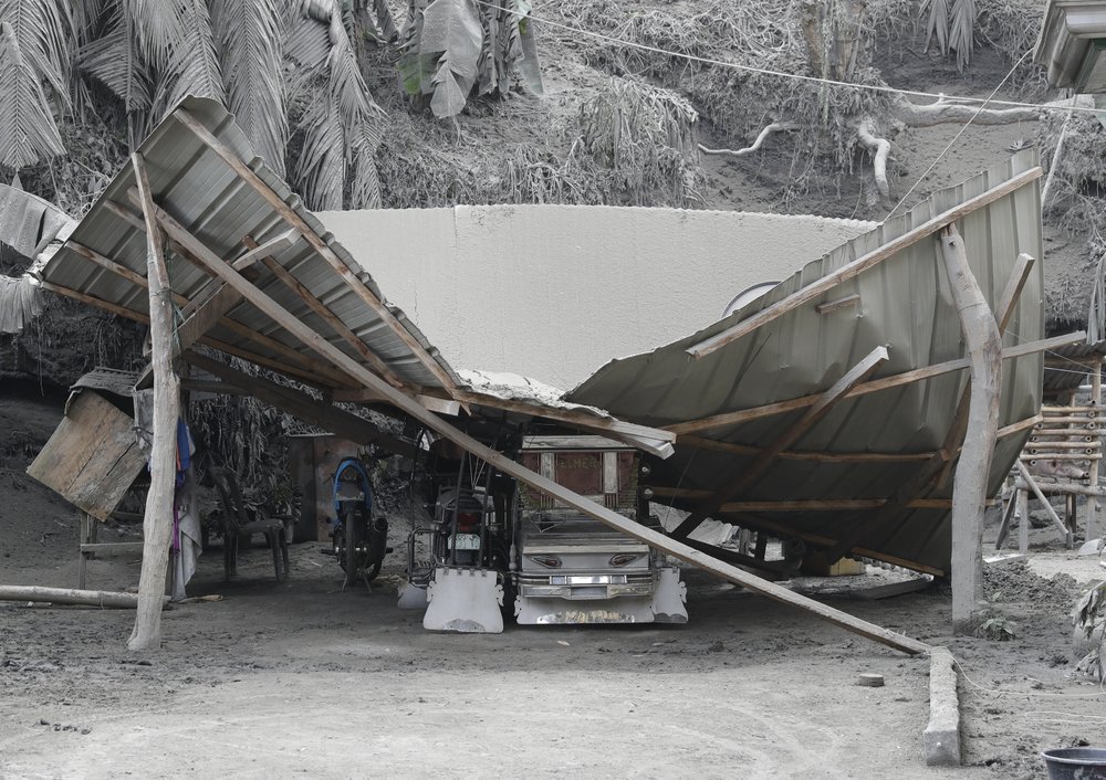 A roof collapses on a pedicab as volcanic ash covers a village at Laurel, Batangas province, southern Philippines on Tuesday, Jan. 14, 2020. Taal volcano is spewing ash half a mile high and trembling with earthquakes constantly as thousands of people flee villages darkened and blanketed by heavy ash.