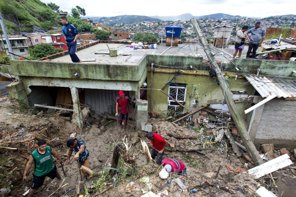 Locals work to clean up mud and debris around houses destroyed by a landslide after heavy rains in Vila Ideal neighborhood, Ibirite municipality, Minas Gerias state, Brazil, Saturday, Jan.25, 2020. Heavy rains caused flooding and landslides in southeast Brazil, killing at least 30 people, authorities said Saturday. 