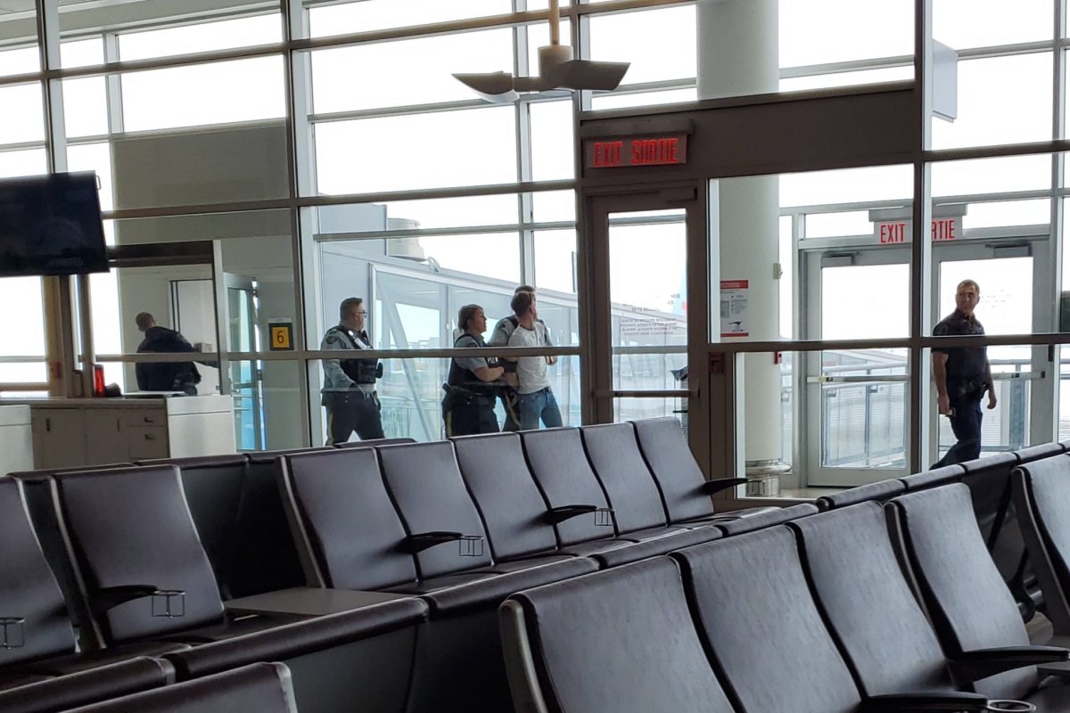 A passenger is escorted off Flight BY32 in Winnipeg.