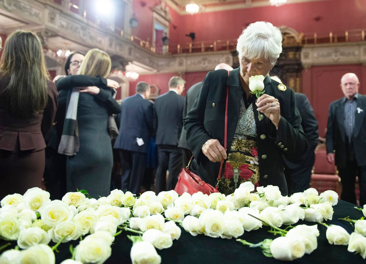 Suzanne Laplante Edward, mother of victim Anne-Marie Edward, smells a rose as she looks at the roses that were laid in commemoration during a ceremony marking the 30th anniversary of the Polythecnique shooting, Thursday, December 5, 2019. 