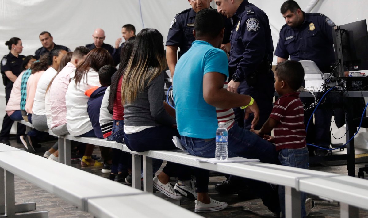 FILE - In this Sept. 17, 2019, file photo, migrants who are applying for asylum in the United States go through a processing area at a new tent courtroom at the Migration Protection Protocols Immigration Hearing Facility, in Laredo, Texas.