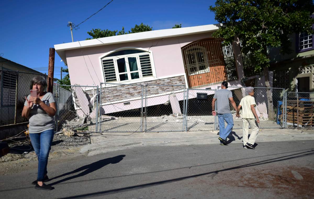 Residents survey damage where a home partially collapsed after an earthquake hit Guanica, Puerto Rico, Monday, Jan. 6, 2020. (AP Photo/Carlos Giusti)