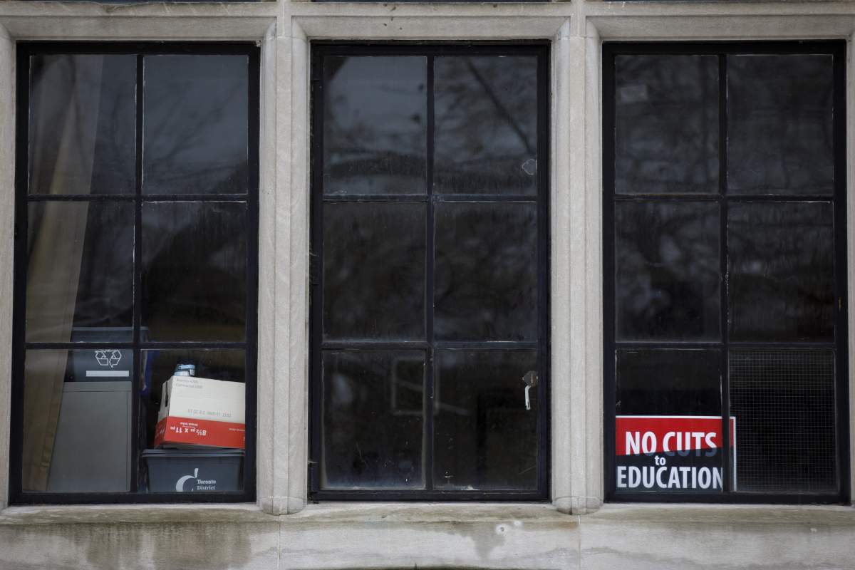 A sign is seen inside a secondary school classroom window as teachers walk the picket line outside in Toronto on December 4, 2019.