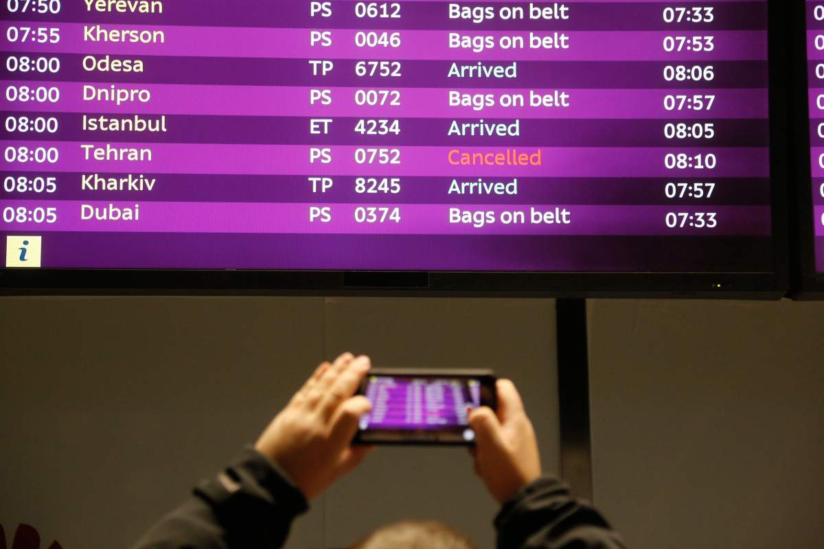 A man takes a photo of the arrivals board with the cancelled fight from Tehran after Ukrainian 737-800 plane crashed on the outskirts of Tehran, Iran, at Borispil international airport outside Kyiv, Ukraine, Wednesday, Jan. 8, 2020. A Ukrainian airplane carrying 176 people crashed on Wednesday shortly after takeoff from Tehran’s main airport, killing all onboard, Iranian state TV and officials in Ukraine said.