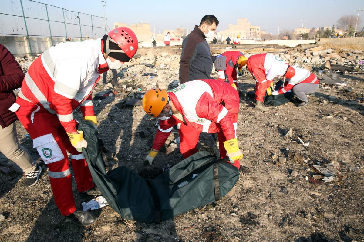 Members of the International Red Crescent collect the bodies of victims around the wreckage after a Ukrainian airliner crashed near Imam Khomeini Airport in Tehran, killing everyone on board on Jan. 8, 2020.