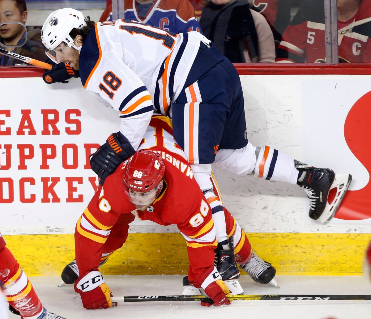 Edmonton Oilers' James Neal, top, knocks down Calgary Flames' Andrew Mangiapane during first period NHL hockey action in Calgary, Alta., Saturday, Jan. 11, 2020. THE CANADIAN PRESS/Larry MacDougal.