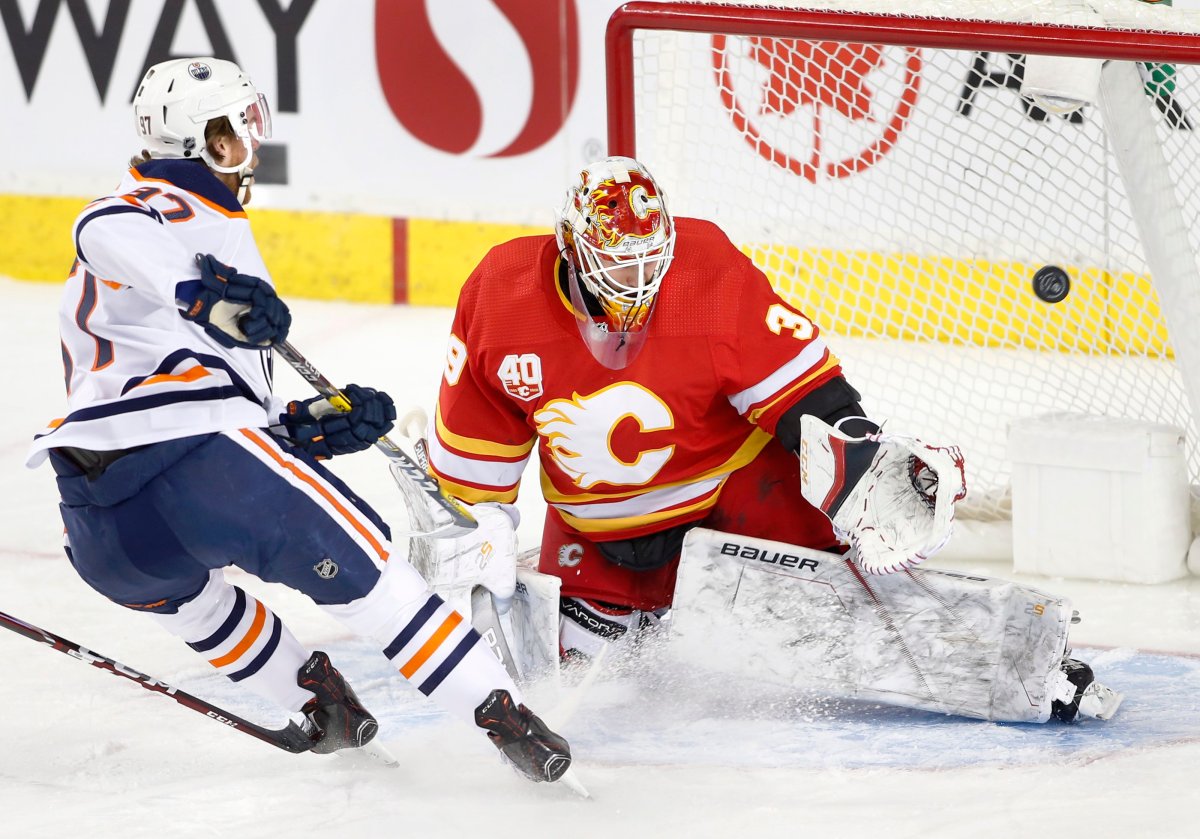 Edmonton Oilers' Connor McDavid, left, scores on Calgary Flames goalie Cam Talbot during first period NHL hockey action in Calgary, Alta., Saturday, Jan. 11, 2020. THE CANADIAN PRESS/Larry MacDougal.