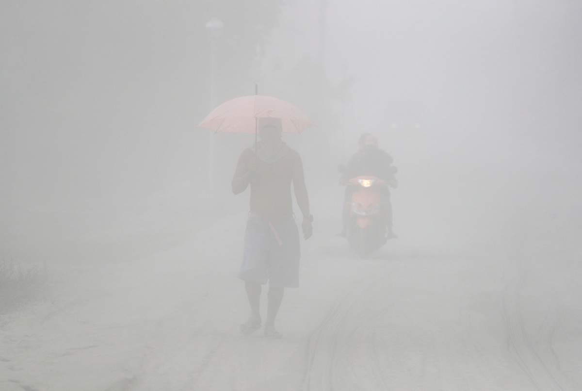 A man walks through a cloud of volcanic ash as he evacuates to safer grounds as Taal volcano in Tagaytay, Cavite province, southern Philippines on Monday, Jan. 13, 2020.