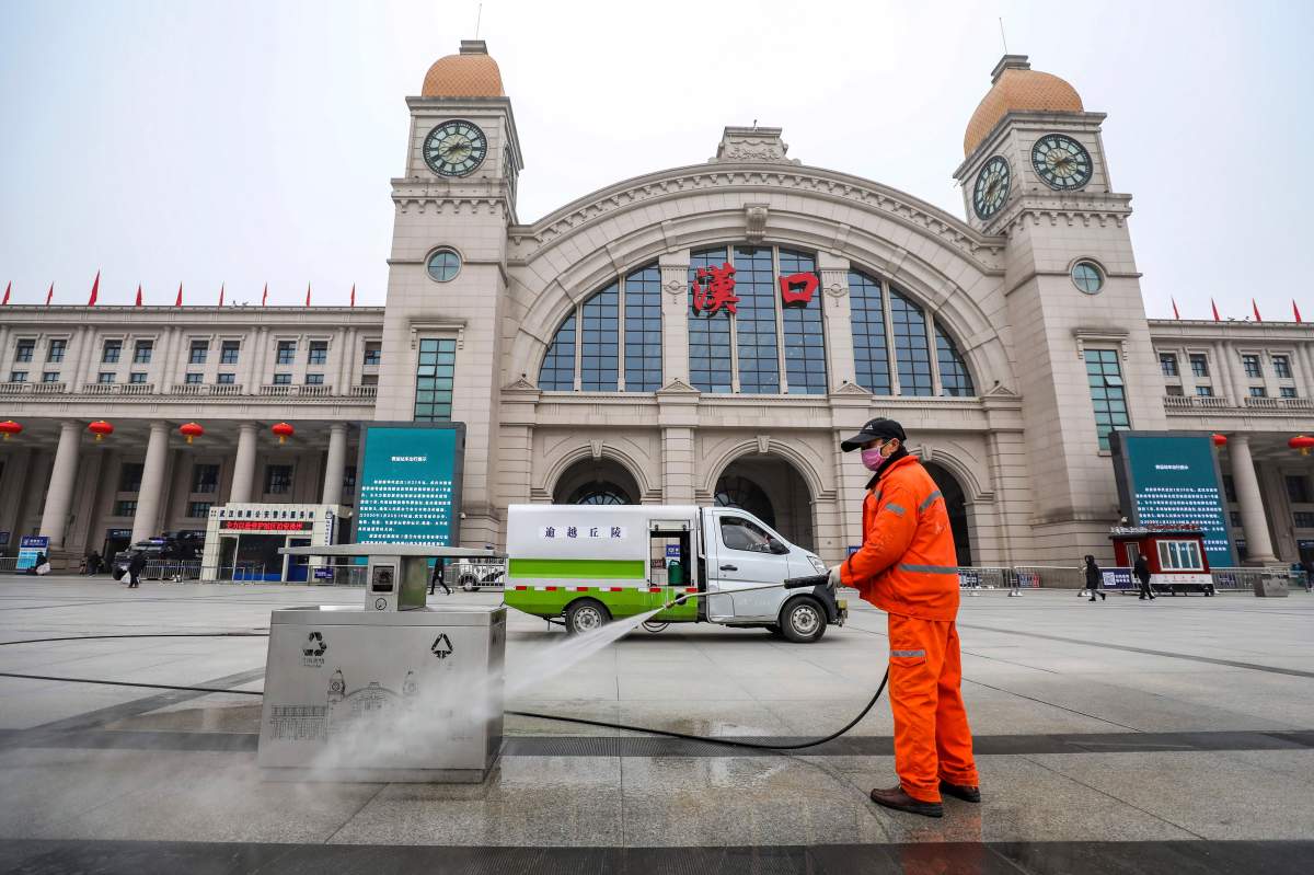 A worker hoses down garbage bins outside the closed Hankou Railway Station in Wuhan in central China’s Hubei Province, Thursday, Jan. 23, 2020.