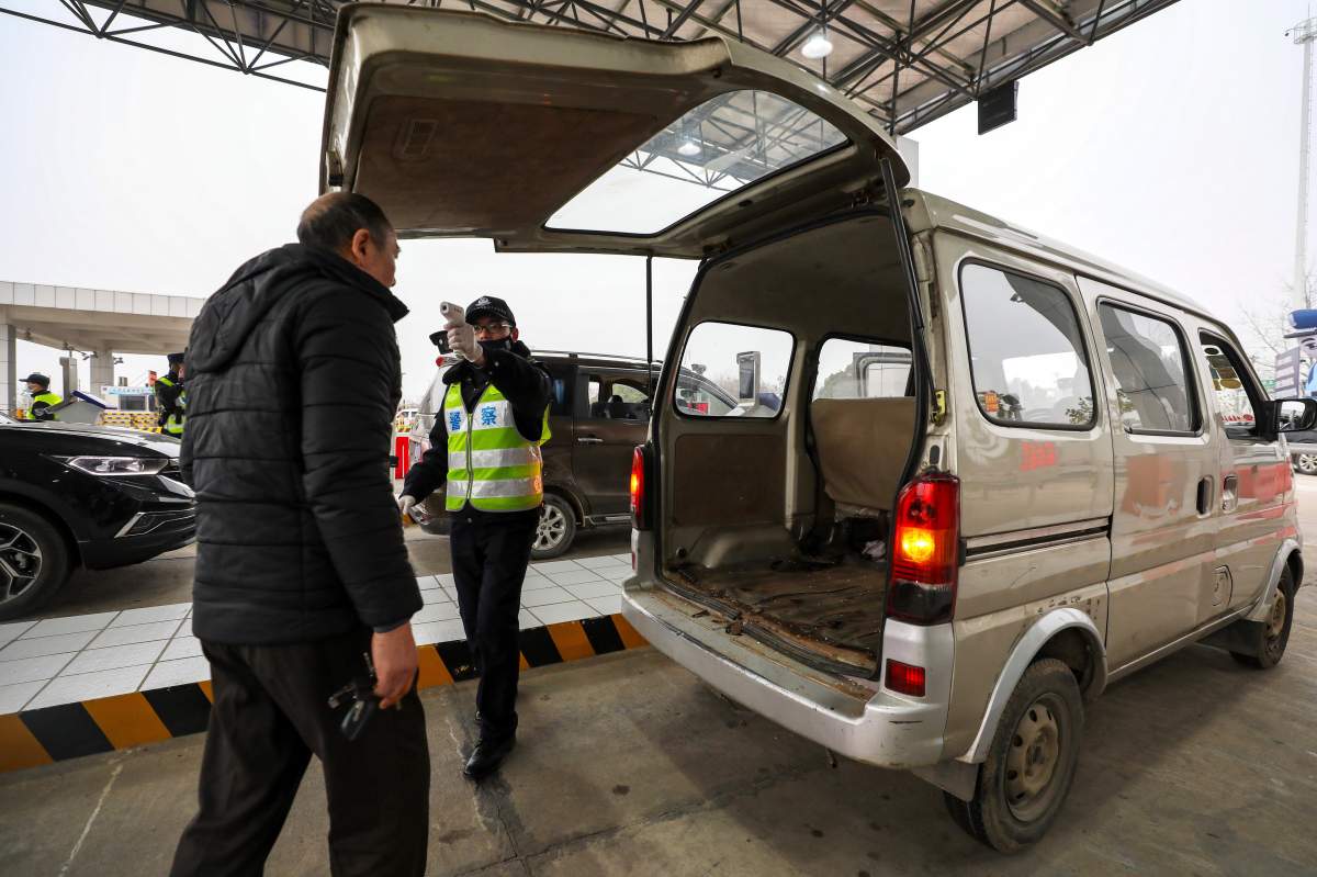 A policeman uses a digital thermometer to take a driver’s temperature at a checkpoint at a highway toll gate in Wuhan in central China’s Hubei Province, Thursday, Jan. 23, 2020.