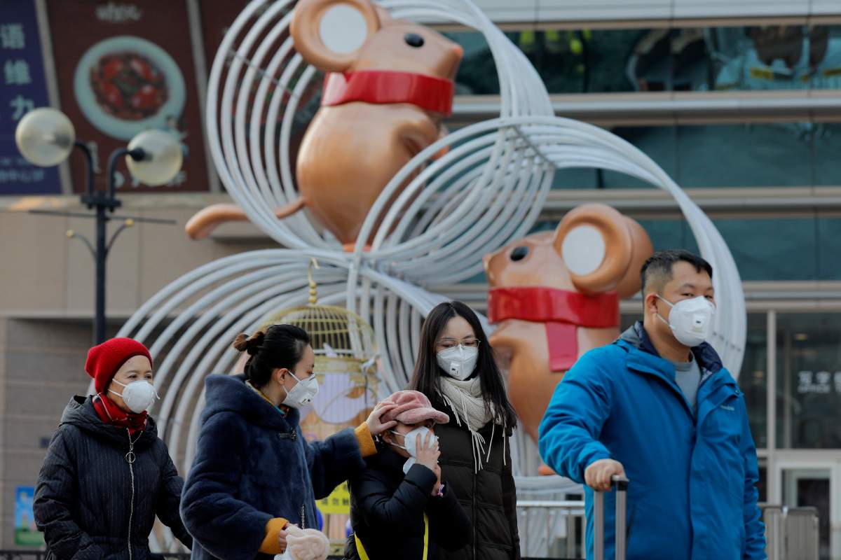 People wear masks as they walk past rat sculptures outside a shopping mall after Chinese New Year celebrations were cancelled in Beijing, China, 25 January 2020.