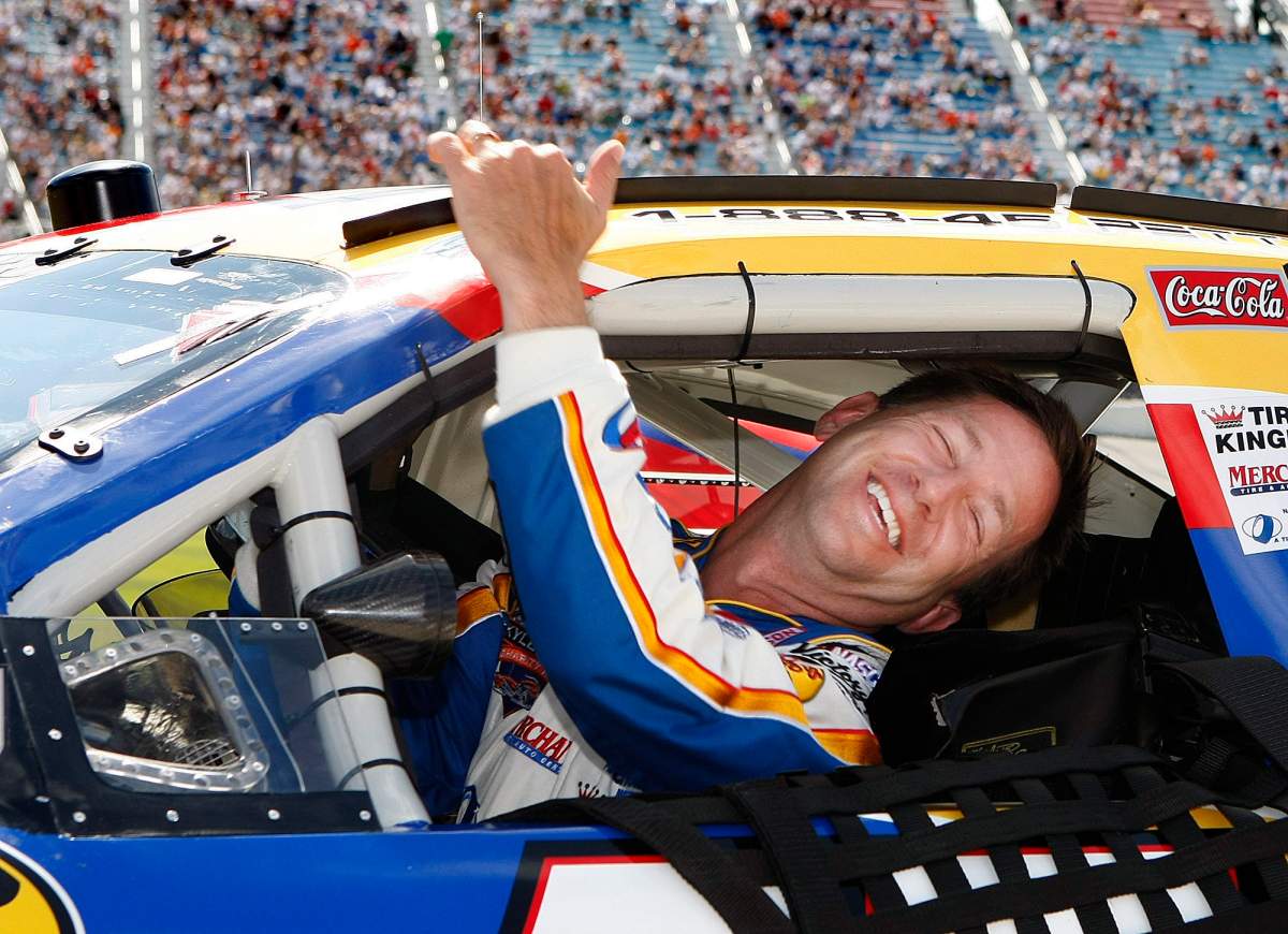 In this July 13, 2007, file photo, John Andretti smiles as he climbs from his car after qualifying for the NASCAR auto race at Chicagoland Speedway in Joliet, Ill. (AP Photo/Warren Wimmer/ File)