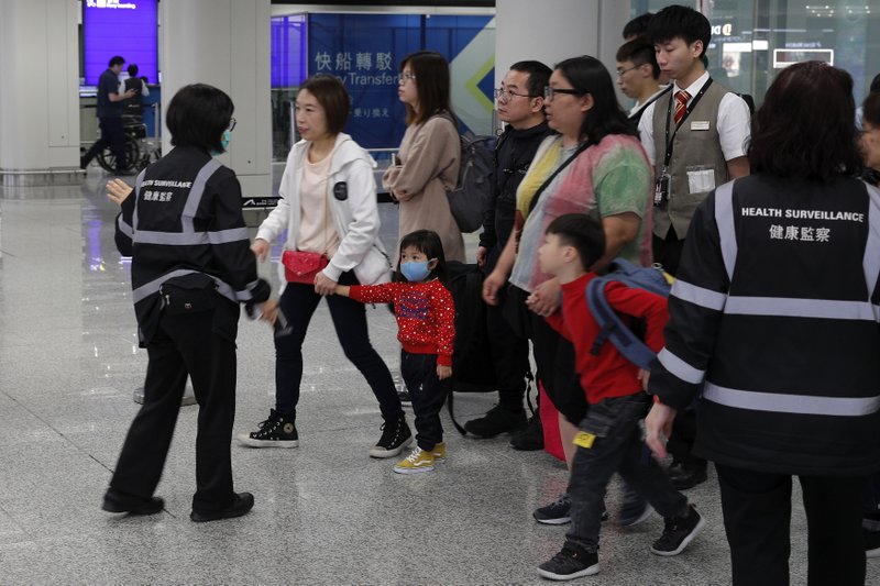 Health surveillance officer use device to check temperature of passengers before the immigration counters at International airport in Hong Kong, Saturday, Jan. 4, 2020. Hong Kong authorities activated a newly created "serious response" level Saturday as fears spread about a mysterious infectious disease that may have been brought back by visitors to a mainland Chinese city. 