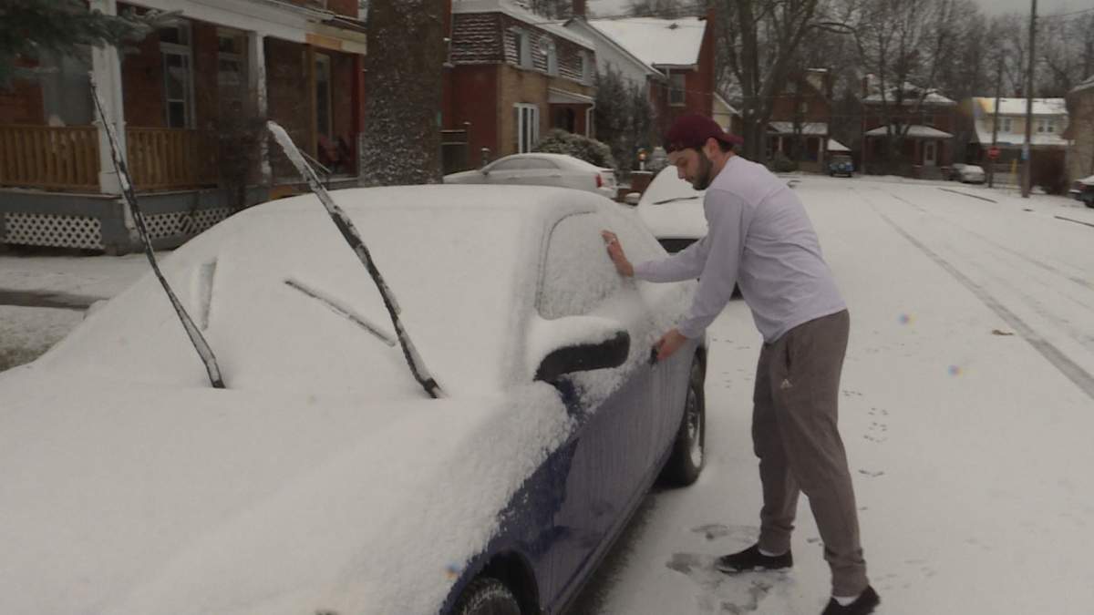 Queen’s University alumnus, Lukas Sacco, tries to get into his car caked in snow and ice