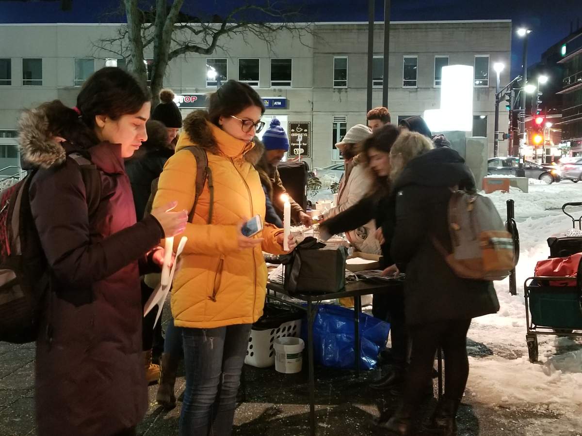 Residents place candles at the foot of a memorial for the victims of the Iran plane crash during a vigil outside the Halifax Central Library on Jan. 22, 2019.
