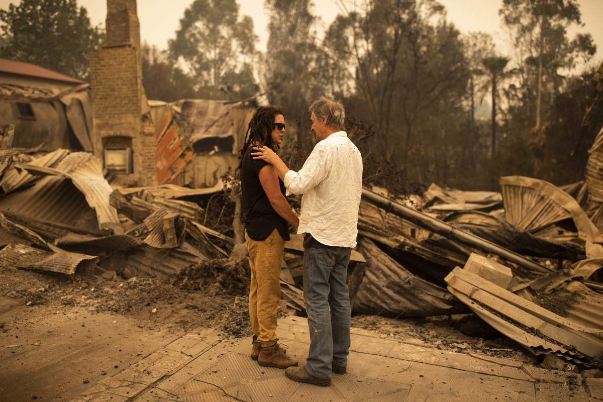Business owners stand in front of their shop, which was destroyed by a bushfire in Cobargo, New South Wales, Australia, Jan. 1, 2020.