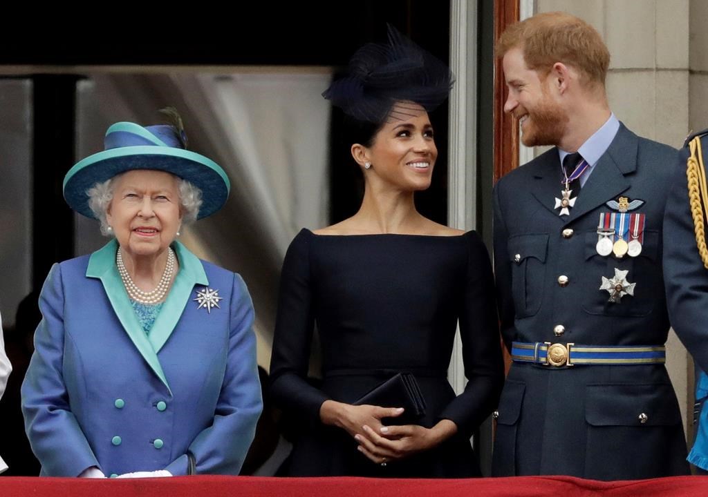 Britain's Queen Elizabeth II, and Meghan the Duchess of Sussex and Prince Harry watch a flypast of Royal Air Force aircraft pass over Buckingham Palace in London on Tuesday, July 10, 2018.