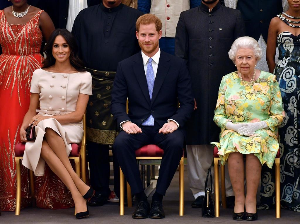 Britain's Queen Elizabeth, Prince Harry and Meghan, Duchess of Sussex pose for a group photo at the Queen's Young Leaders Awards Ceremony at Buckingham Palace in London on Tuesday, June 26, 2018.