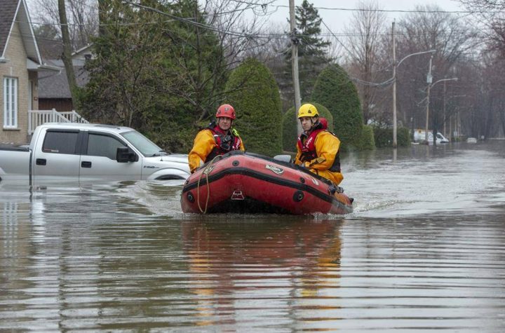 Firefighters make their way through a flooded street on Friday, May 3, 2019 in Ste-Marthe-sur-la-Lac, Quebec. A federal review says the government had trouble spending half of the $184 million earmarked to prevent flood damage in Canadian communities. THE CANADIAN PRESS/Ryan Remiorz.