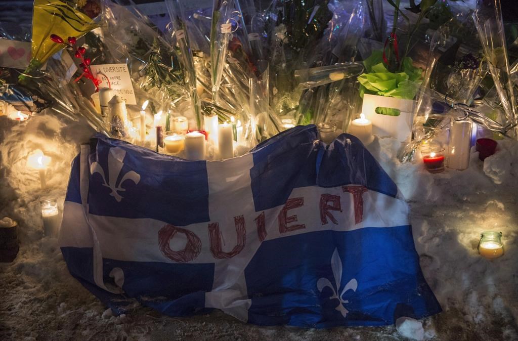 A Quebec flag with the word 'Open' written on it is shown in remembrance of six victims of a shooting at mosque during a vigil in Quebec City on Jan. 30, 2017.