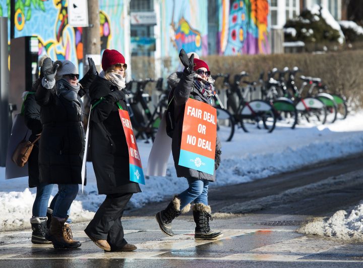 Teachers of the Elementary Teachers' Federation of Ontario wave to honking cars as they participate in a full withdrawal of services strike in Toronto on January 20, 2020.