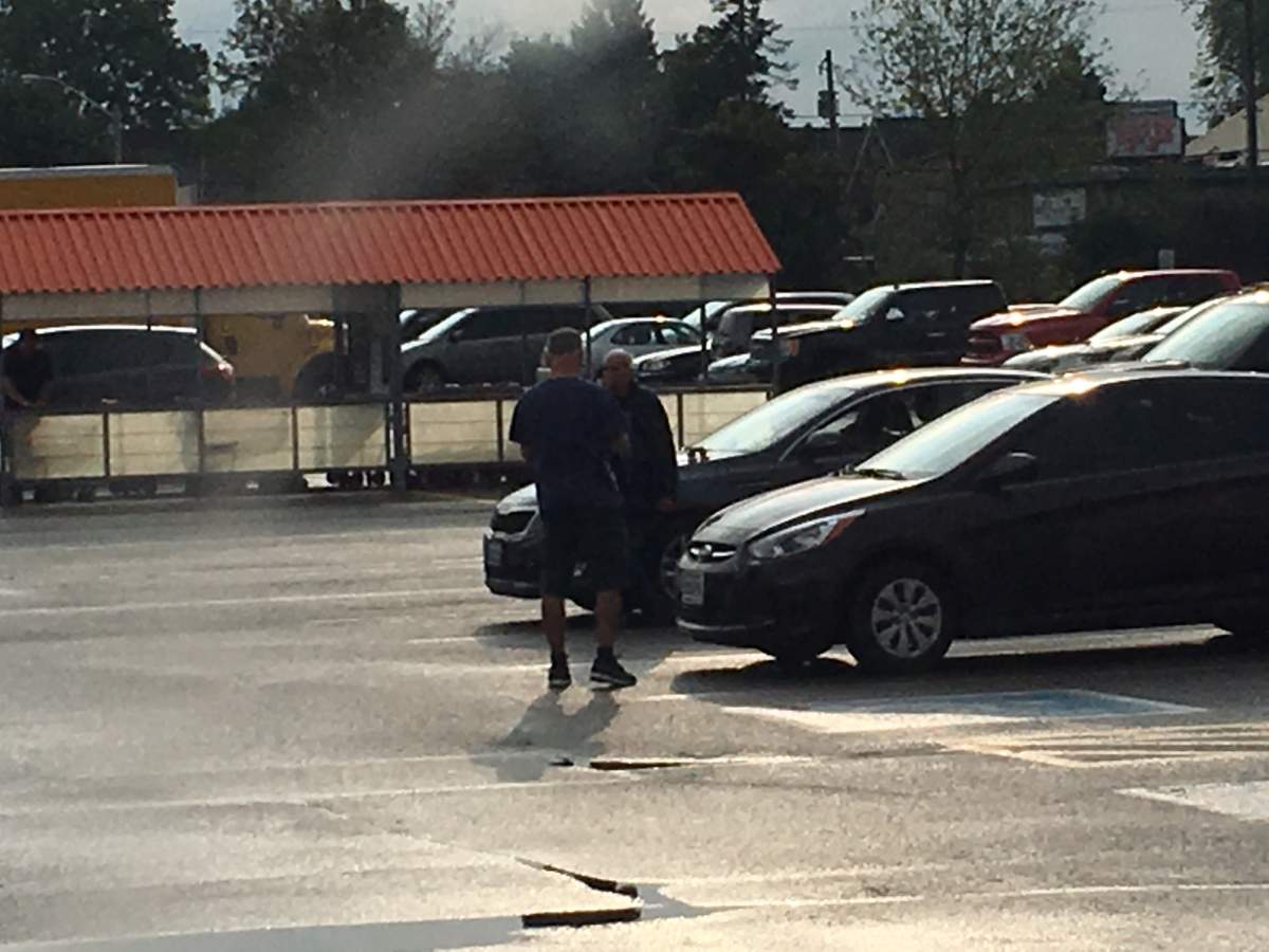 A man approaches Terrance Finn (facing) on the morning of Aug. 22, 2018 in the parking lot of Home Depot in Peterborough.