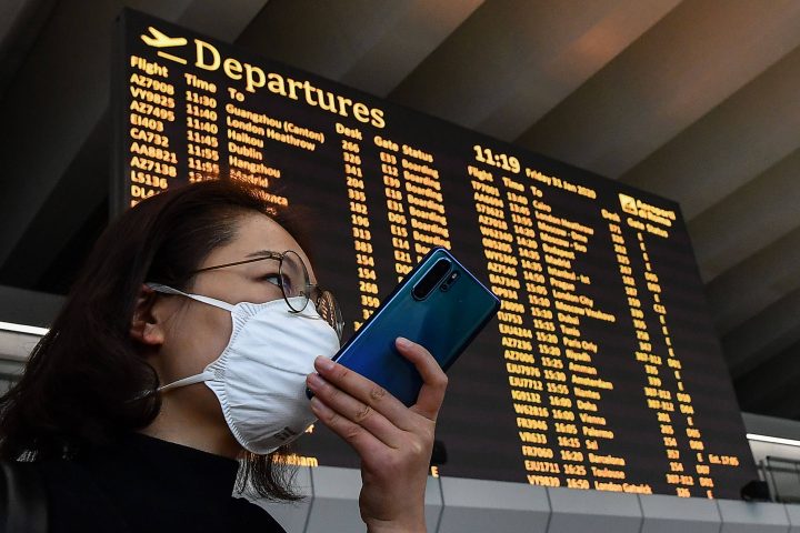 A passenger wearing a respiratory mask speaks on her smartphone by the departures board on January 31, 2020 at Rome's Fiumicino airport, as a number of airlines halted or reduced flights to China as the country struggles to contain the spread of the deadly novel coronavirus. - The Italian government said on January 30, 2020 it was suspending all flights between Italy and China, adding it was the first EU government to do so. China has advised its citizens to postpone trips abroad and cancelled overseas group tours, while several countries have urged their citizens to avoid travel to China. (Photo by Tiziana FABI / AFP) (Photo by TIZIANA FABI/AFP via Getty Images).