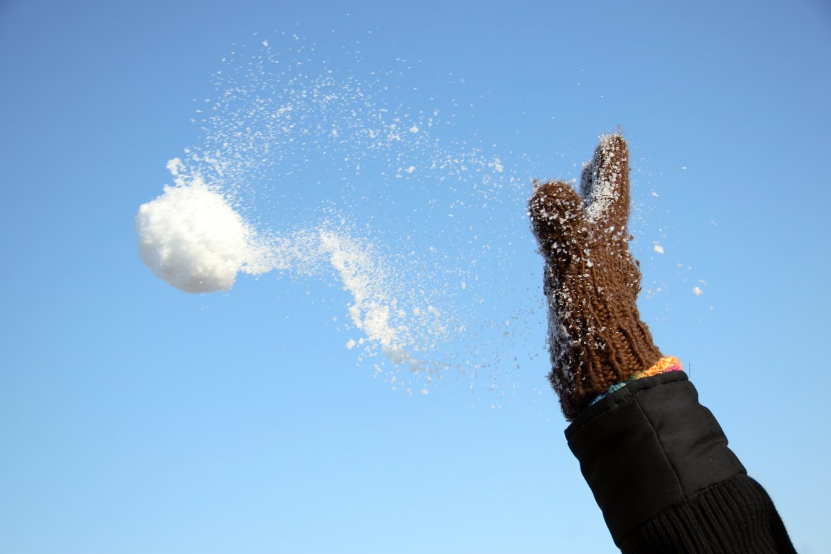 Close-up of a gloved hand throwing a snowball. 