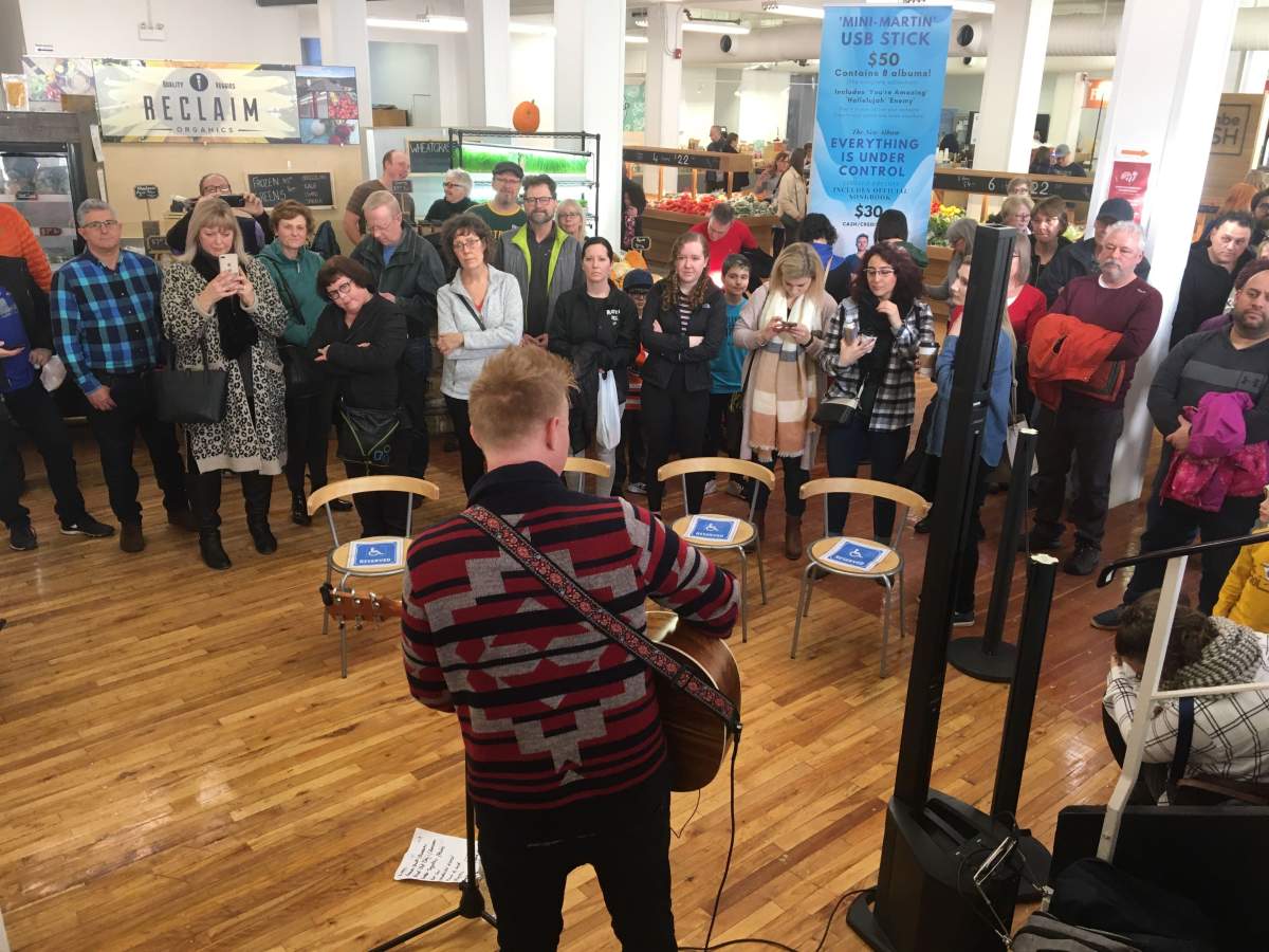 A crowd gathers around Martin Kerr as he performs.
