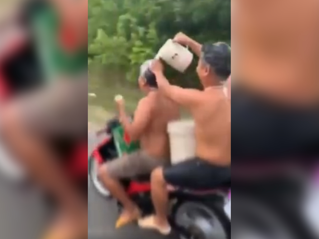 A video shows two men in Vietnam taking a shower on a motorcycle.