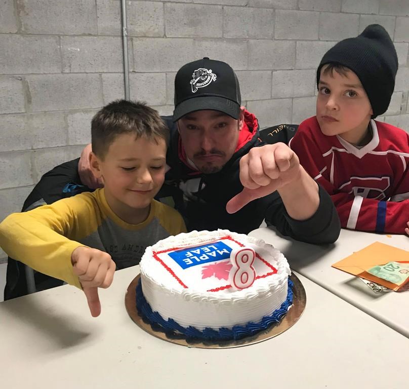 Eight-year-old Jacob Bertrand (left) poses with his father Mathieu Bertrand and a friend in a handout photo. His family ordered a Toronto Maple Leafs cake for Jacob’s birthday and got a cake with a Maple Leaf Foods logo instead.
