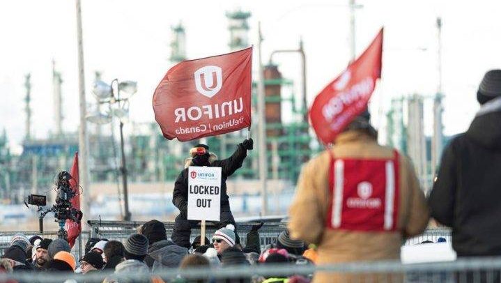 A man holds a Unifor flag during a rally at the Co-op Refinery Complex in Regina on Tuesday, Jan. 21, 2020.