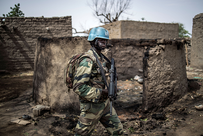 A foot soldier of the 2nd Mechanised Company of the Senegalese Battalion of the MINUSMA (United Nations Multidimensional Integrated Stabilisation Mission in Mali) patrols in the destroyed Fulani village of Bare, on July 5, 2019. (Photo by Marco LONGARI / AFP)