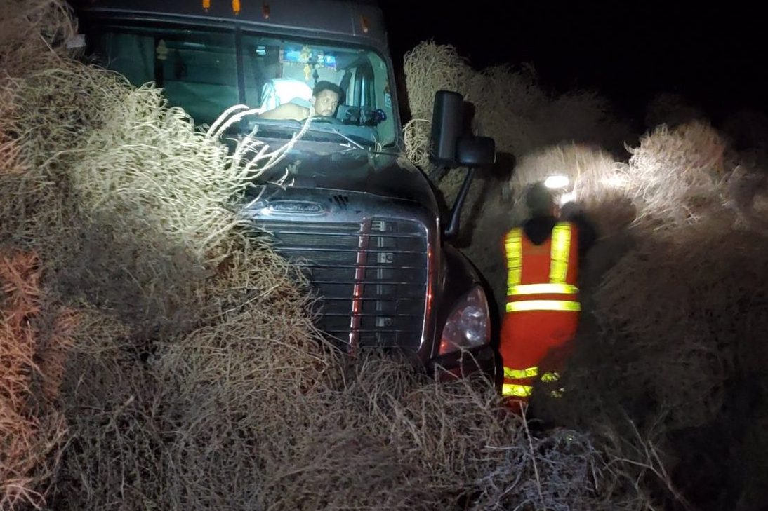 A motorist sits in his vehicle while transportation workers try to dig it out from a pile of tumbleweeds in Washington state on Dec. 31, 2019.