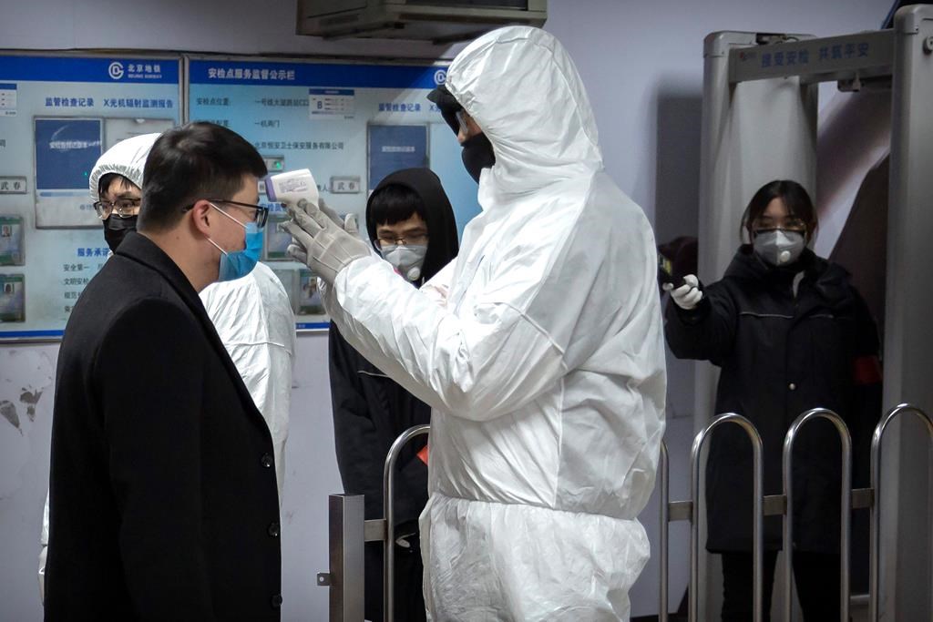 A worker wearing a hazardous materials suit takes the temperature of a passenger at the entrance to a subway station in Beijing, Sunday, Jan. 26, 2020. The new virus accelerated its spread in China, and the U.S. Consulate in the epicentre of the outbreak, the central city of Wuhan, announced Sunday it will evacuate its personnel and some private citizens aboard a charter flight.