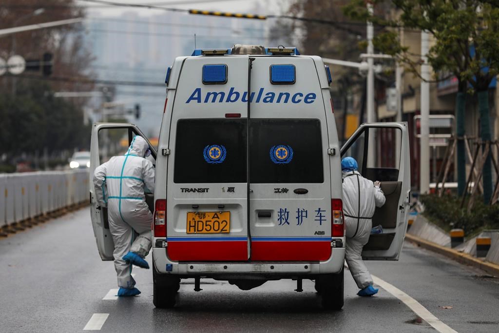 In this Sunday, Jan. 26, 2020 photo, ambulance crew members in protective gear get into their ambulance in Wuhan in central China's Hubei Province.