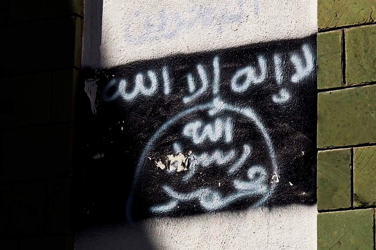 This Oct. 16, 2017 photo shows the black al-Qaida flag is sprayed on the wall of a damaged school that was turned into a religious court, in Taiz, Yemen.