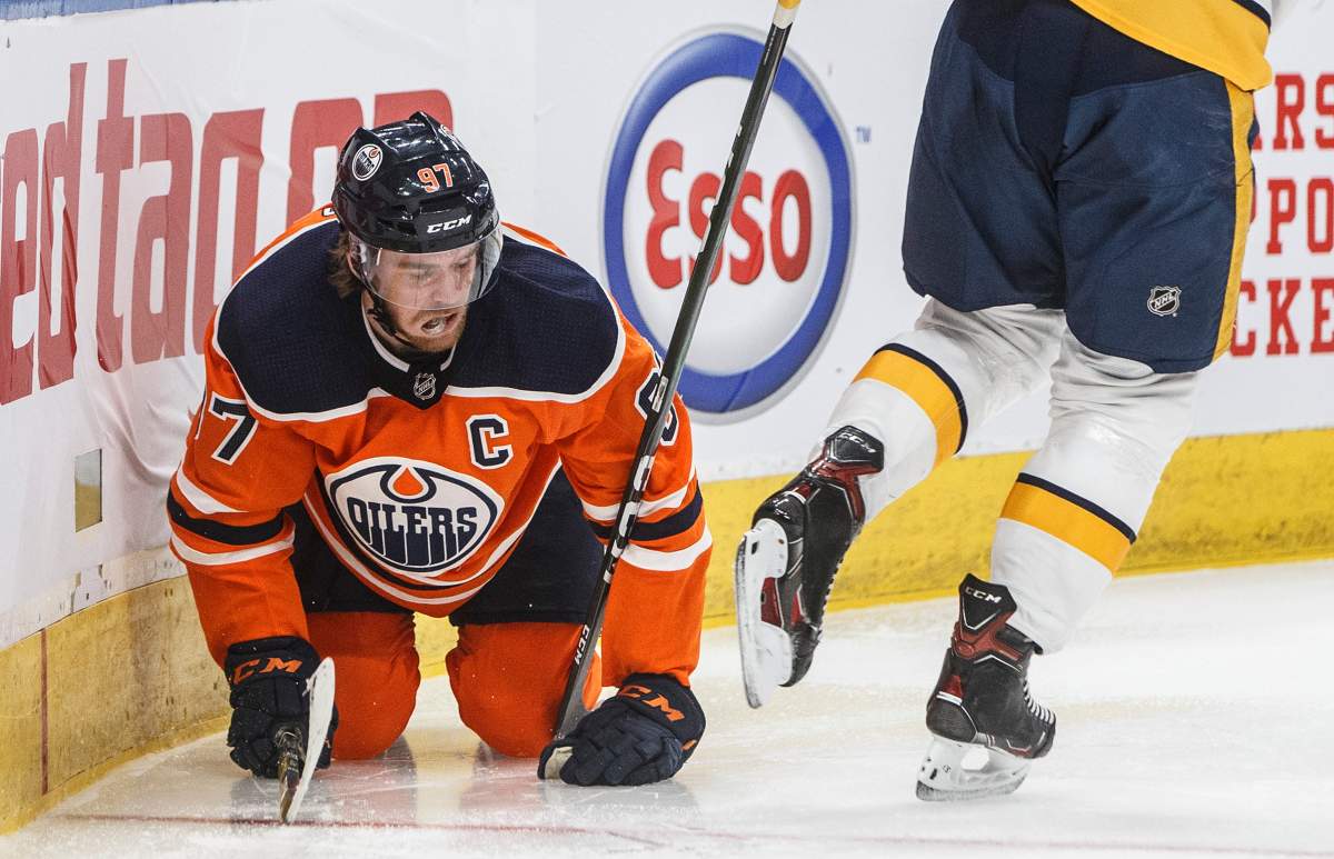 Edmonton Oilers' Connor McDavid (97) gets up slowly after going into the boards against the Nashville Predators during second period NHL action in Edmonton, Alta., on Saturday, February 8, 2020. Edmonton captain Connor McDavid will be out two to three weeks with a quad injury. THE CANADIAN PRESS/Jason Franson.