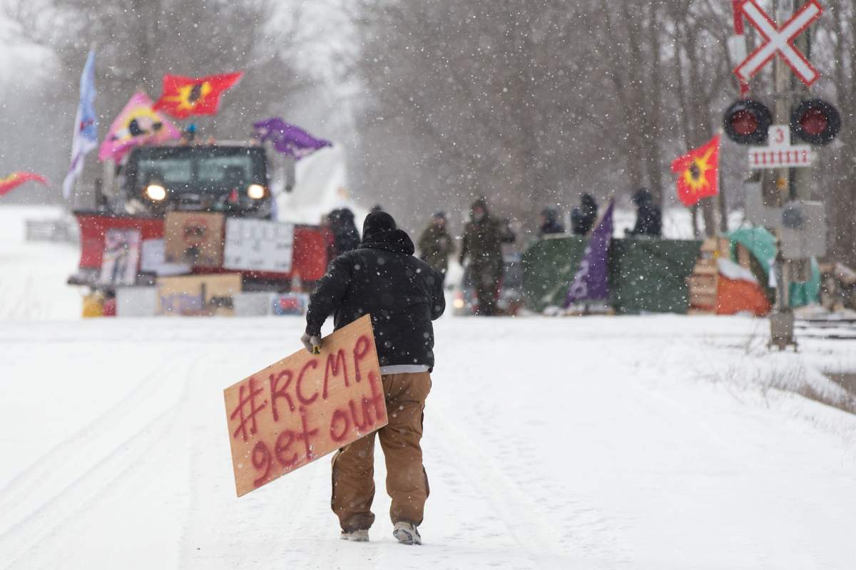 A protester carries a sign at a rail blockade on the 10th day of demonstration in Tyendinaga, near Belleville, Ont., Feb. 15, 2020.