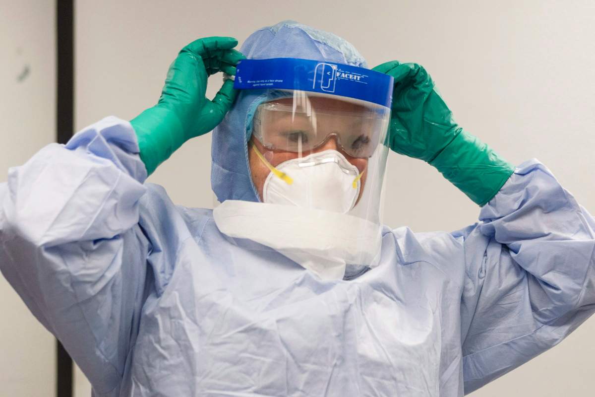 A healthcare professional adjusts her mask during a demonstration of Personal Protective Equipment (PPE) procedures at Toronto Western Hospital on October 17, 2014. 