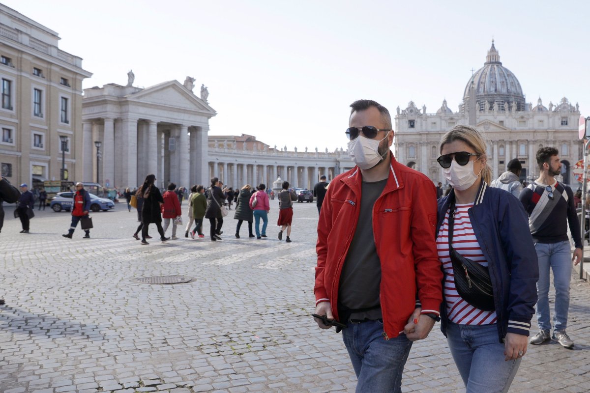 A couple wearing face masks, stroll outside St. Peter's Square, at the Vatican, Thursday, Feb. 27, 2020.