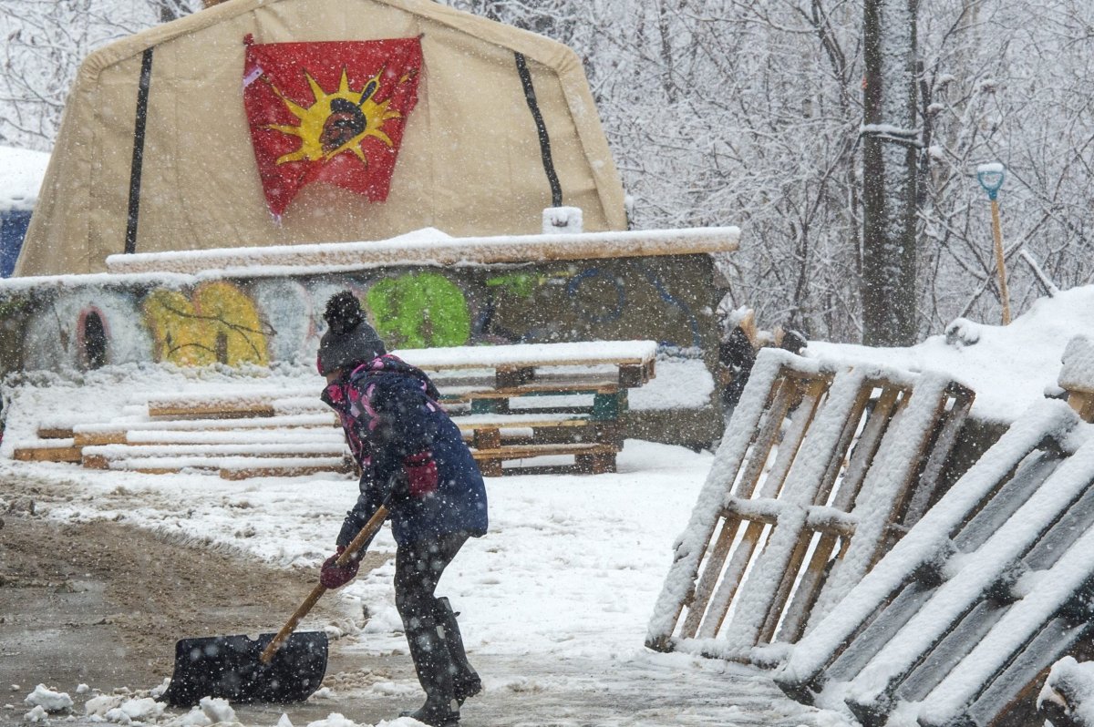 Protesters in support of the Wet'suwet'en hereditary chiefs clear snow near the entrance to the blockade of the commuter rail line in Kahnawake Mohawk Territory, near Montreal, Thursday, Feb. 27, 2020.