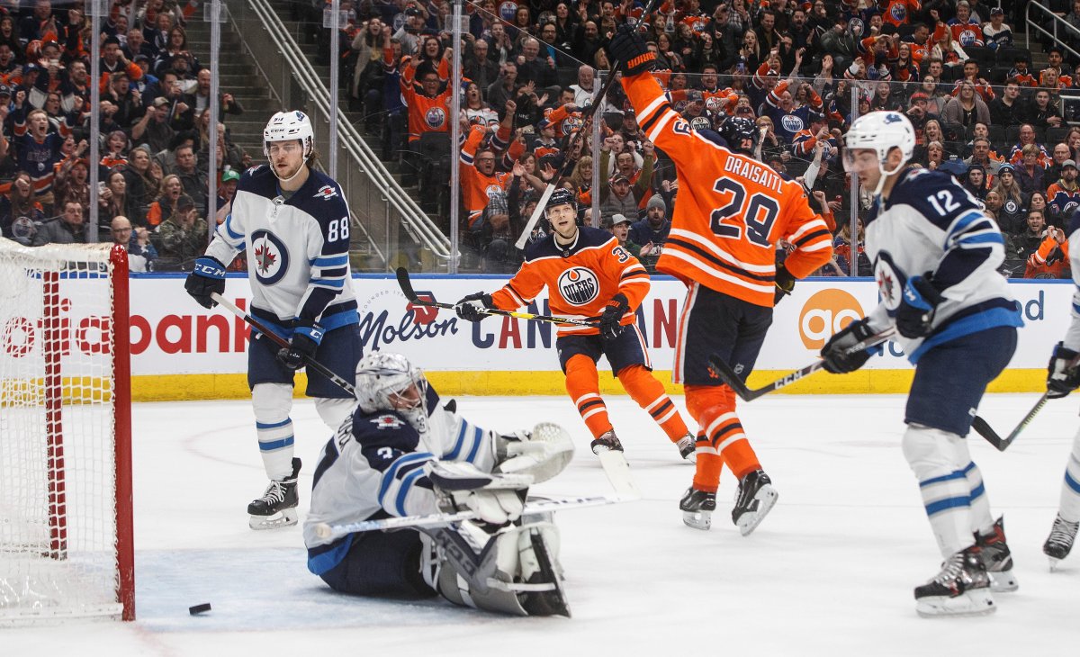 Winnipeg Jets goalie Connor Hellebuyck (37) is scored on as Edmonton Oilers' Leon Draisaitl (29) celebrates the goal during second period NHL action in Edmonton, Saturday, Feb. 29, 2020. THE CANADIAN PRESS/Jason Franson.